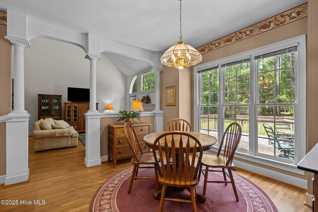 6304 Wolfhead Ct, Wilmington, NC 28411 - dining area featuring ornate columns, a chandelier, light wood-type flooring, and vaulted ceiling
