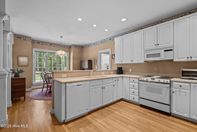 6304 Wolfhead Ct, Wilmington, NC 28411 - kitchen with white appliances, a sink, a peninsula, ornate columns, and light wood-style floors