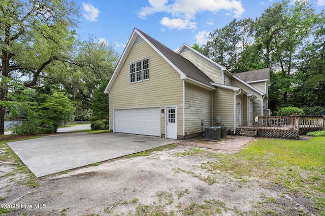 6304 Wolfhead Ct, Wilmington, NC 28411 - view of side of home with an attached garage, a deck, central AC, concrete driveway, and a shingled roof