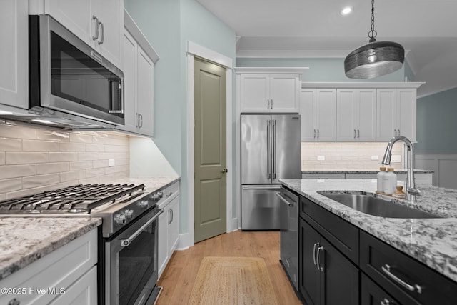 633 Ashbury Dr SE, Bolivia, NC 28422 - kitchen featuring stainless steel appliances, a sink, white cabinetry, light wood-style flooring, and decorative light fixtures