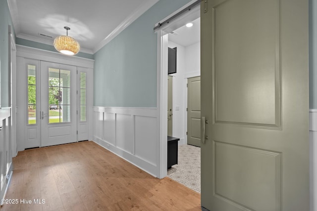 633 Ashbury Dr SE, Bolivia, NC 28422 - entrance foyer featuring crown molding, light wood finished floors, a barn door, wainscoting, and a decorative wall