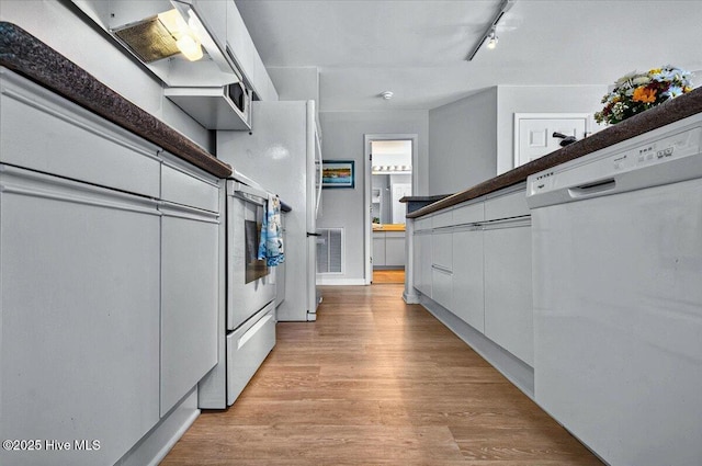 816 Colony Pl Unit D, Sunset Beach, NC 28468 - kitchen with rail lighting, white dishwasher, light wood-type flooring, white cabinets, and modern cabinets