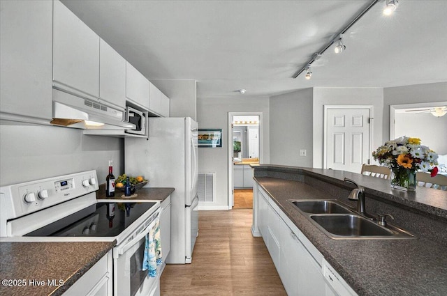816 Colony Pl Unit D, Sunset Beach, NC 28468 - kitchen featuring white electric stove, a sink, dark countertops, under cabinet range hood, and light wood-style flooring