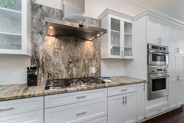 10 Linville Dr, Pinehurst, NC 28374 - kitchen with wall chimney range hood, appliances with stainless steel finishes, backsplash, and glass insert cabinets