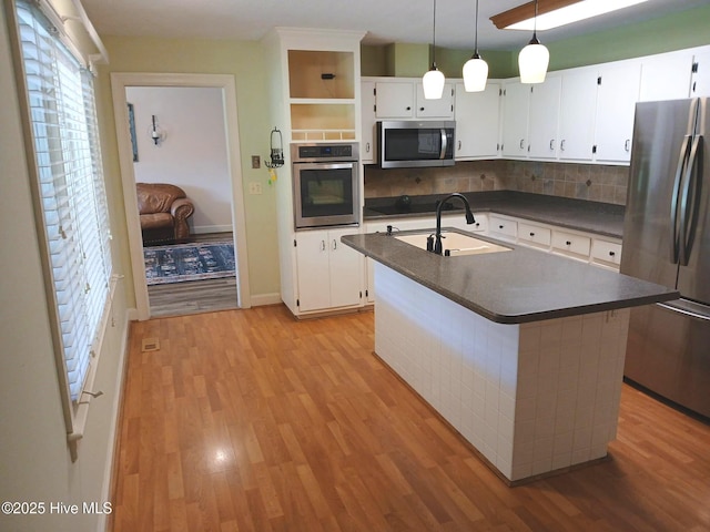3902 Little John Dr N, Wilson, NC 27896 - kitchen featuring appliances with stainless steel finishes, dark countertops, light wood finished floors, a sink, and tasteful backsplash