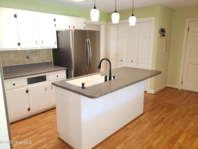 3902 Little John Dr N, Wilson, NC 27896 - kitchen featuring freestanding refrigerator, dark countertops, a sink, light wood finished floors, and white cabinetry