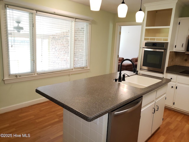3902 Little John Dr N, Wilson, NC 27896 - kitchen featuring stainless steel appliances, a sink, dark countertops, light wood finished floors, and healthy amount of natural light