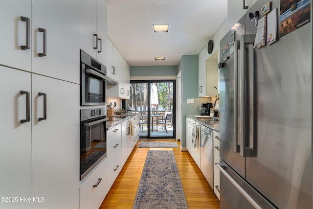 185 Ponte Vedra Dr, Pinehurst, NC 28374 - kitchen featuring appliances with stainless steel finishes, modern cabinets, light wood finished floors, and white cabinetry