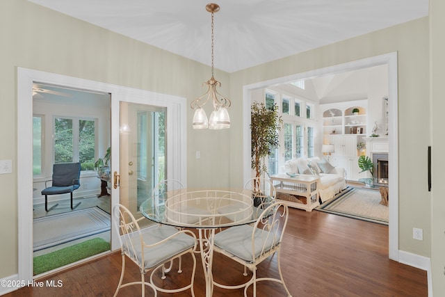 1012 Creekside Ln, Wilmington, NC 28411 - dining space with wood finished floors, a glass covered fireplace, a chandelier, built in shelves, and baseboards