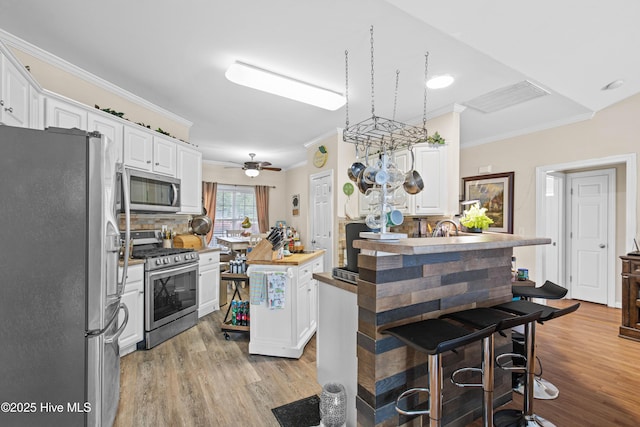600 Pearson Cir, Newport, NC 28570 - kitchen featuring stainless steel appliances, crown molding, light wood-style flooring, and white cabinetry