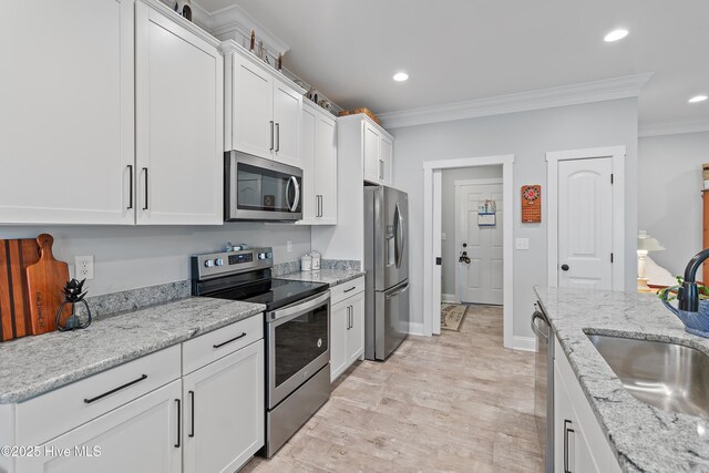 2402 W Oak Island Dr, Oak Island, NC 28465 - kitchen featuring appliances with stainless steel finishes, a sink, ornamental molding, white cabinets, and recessed lighting