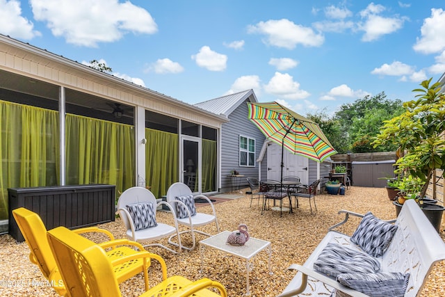 2402 W Oak Island Dr, Oak Island, NC 28465 - view of patio featuring a sunroom, outdoor dining area, and a storage shed