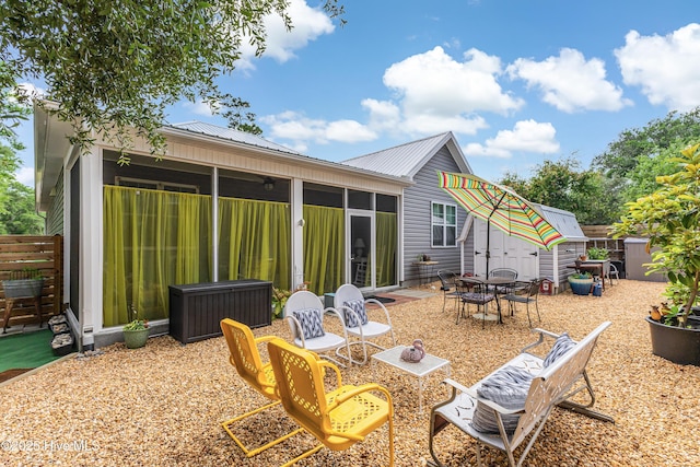 2402 W Oak Island Dr, Oak Island, NC 28465 - back of house with a sunroom, metal roof, outdoor dining area, and a patio area