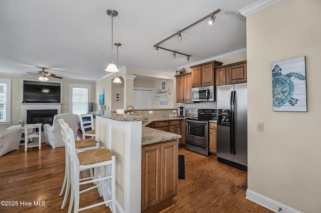 2 Clam Shell Ln Unit 6, Carolina Beach, NC 28428 - kitchen with appliances with stainless steel finishes, a peninsula, a kitchen breakfast bar, a ceiling fan, and brown cabinets