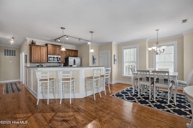 2 Clam Shell Ln Unit 6, Carolina Beach, NC 28428 - kitchen with stainless steel appliances, wood finished floors, a breakfast bar area, a chandelier, and crown molding