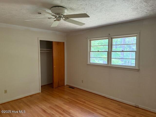430 W Rhode Island Ave, Southern Pines, NC 28387 - unfurnished bedroom with light wood-style flooring, a textured ceiling, baseboards, a closet, and a ceiling fan