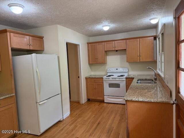 430 W Rhode Island Ave, Southern Pines, NC 28387 - kitchen featuring white appliances, a sink, light wood-style floors, a textured ceiling, and light stone counters