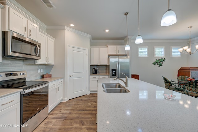 1337 Fence Post Ln, Carolina Shores, NC 28467 - kitchen with appliances with stainless steel finishes, a sink, wood finished floors, white cabinets, and decorative light fixtures