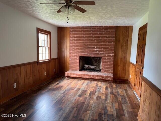 214 NC Highway 561 E, Ahoskie, NC 27910 - unfurnished living room featuring a textured ceiling, ceiling fan, wood finished floors, a fireplace, and wooden walls