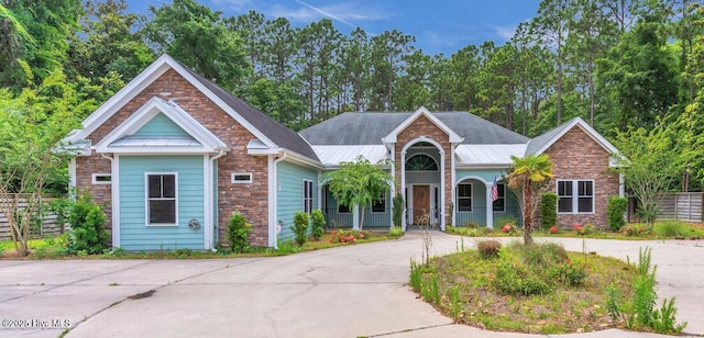 1120 Beasley Rd, Wilmington, NC 28409 - view of front facade featuring stone siding, a porch, and curved driveway