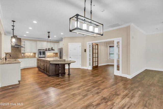 1120 Beasley Rd, Wilmington, NC 28409 - kitchen with stainless steel appliances, crown molding, tasteful backsplash, wall chimney exhaust hood, and dark wood finished floors
