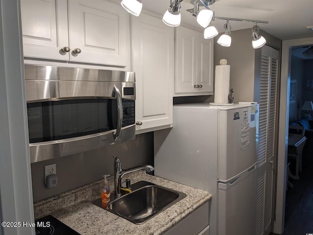 7500 N Ocean Blvd Unit 6061, Myrtle Beach, SC 29572 - kitchen featuring a sink, stainless steel microwave, white cabinetry, freestanding refrigerator, and light stone countertops