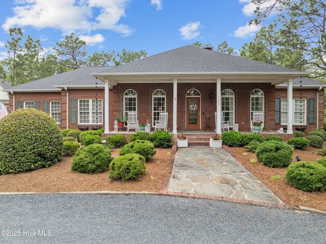 155 Mckenzie Rd E, Pinehurst, NC 28374 - view of front of property featuring brick siding, a porch, and a shingled roof