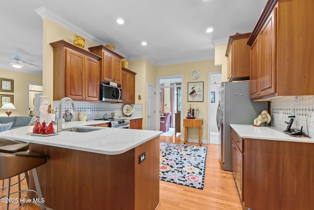 155 Mckenzie Rd E, Pinehurst, NC 28374 - kitchen featuring appliances with stainless steel finishes, a sink, a breakfast bar area, a peninsula, and ornamental molding