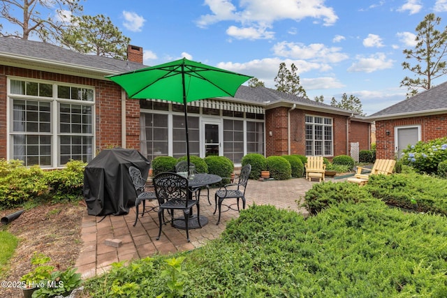 155 Mckenzie Rd E, Pinehurst, NC 28374 - back of property featuring brick siding, a patio, a chimney, and a shingled roof