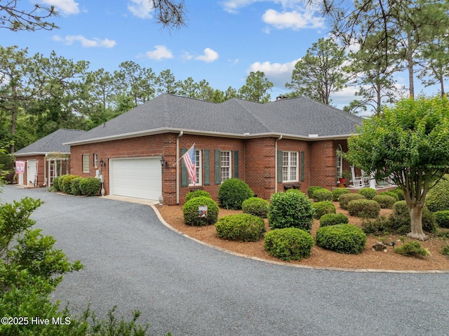 155 Mckenzie Rd E, Pinehurst, NC 28374 - view of front facade featuring brick siding, an attached garage, driveway, and roof with shingles