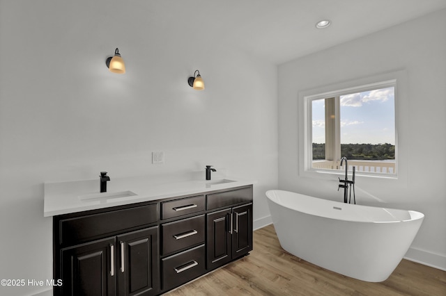 232 Shell Dr, Sneads Ferry, NC 28460 - bathroom featuring a freestanding bath, wood finished floors, double vanity, baseboards, and recessed lighting