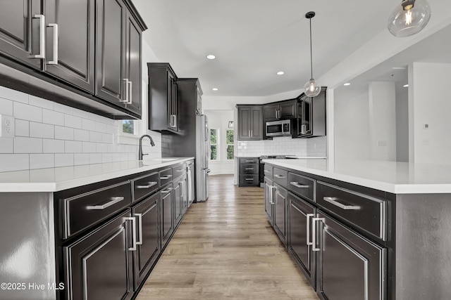 232 Shell Dr, Sneads Ferry, NC 28460 - kitchen with stainless steel appliances, a sink, light wood-type flooring, decorative backsplash, and light countertops