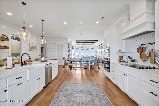 1753 New River Inlet Rd, North Topsail Beach, NC 28460 - kitchen with stainless steel appliances, custom exhaust hood, a sink, white cabinetry, and light wood finished floors