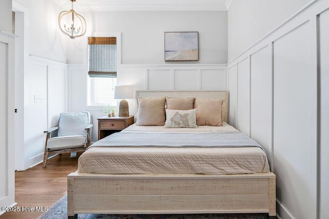 1753 New River Inlet Rd, North Topsail Beach, NC 28460 - bedroom with a decorative wall, wood finished floors, wainscoting, a chandelier, and ornamental molding
