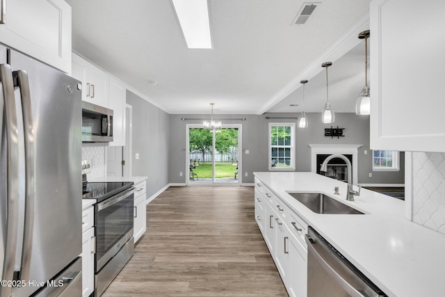 422 Point View Ct, Wilmington, NC 28411 - kitchen with stainless steel appliances, a sink, a chandelier, white cabinets, and light wood-style floors