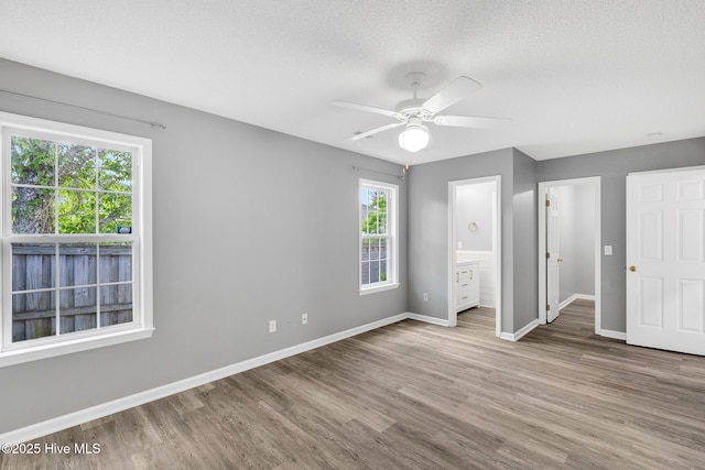 422 Point View Ct, Wilmington, NC 28411 - unfurnished bedroom with wood finished floors, baseboards, connected bathroom, a ceiling fan, and a textured ceiling