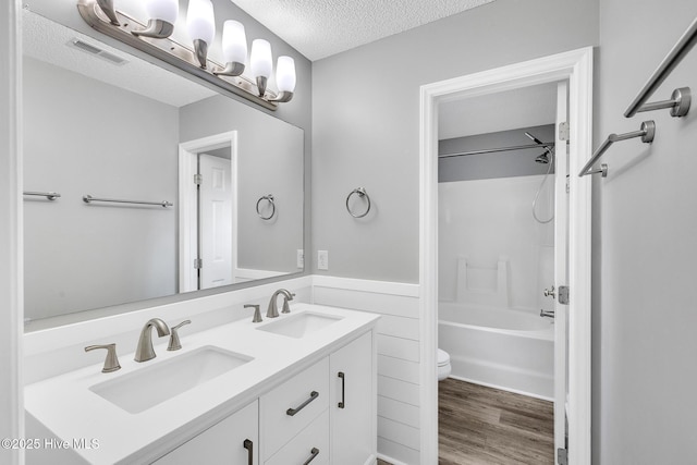 422 Point View Ct, Wilmington, NC 28411 - bathroom with a textured ceiling, toilet, double vanity, wood finished floors, and shower / washtub combination