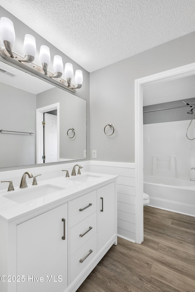 422 Point View Ct, Wilmington, NC 28411 - bathroom featuring wainscoting, double vanity, wood finished floors, toilet, and a textured ceiling
