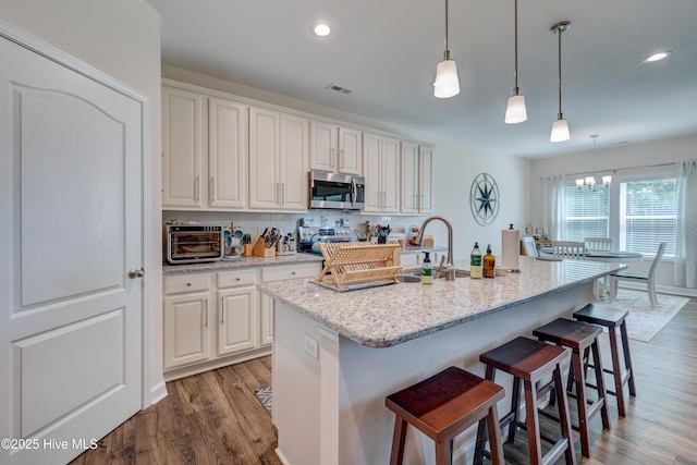 14 Thrush Trl, Hampstead, NC 28443 - kitchen with stainless steel microwave, wood finished floors, decorative backsplash, a kitchen breakfast bar, and hanging light fixtures