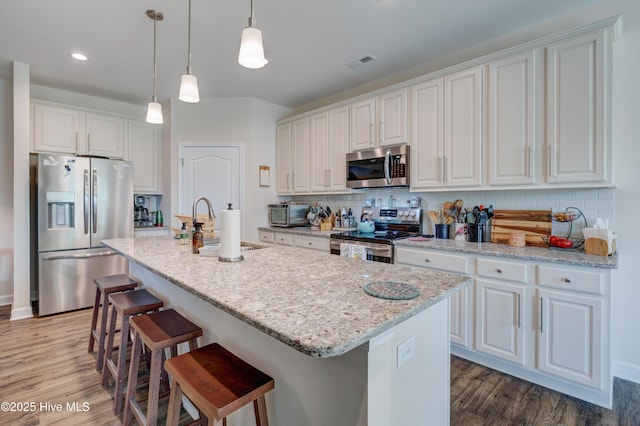 14 Thrush Trl, Hampstead, NC 28443 - kitchen featuring stainless steel appliances, wood finished floors, tasteful backsplash, white cabinets, and recessed lighting