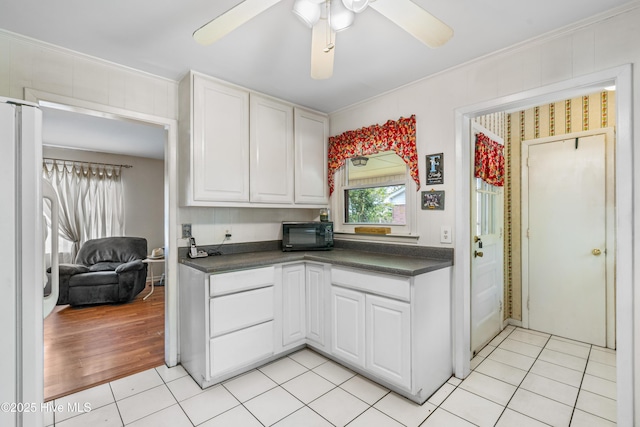 525 Mohican Trl, Wilmington, NC 28409 - kitchen with freestanding refrigerator, dark countertops, black microwave, white cabinetry, and ornamental molding