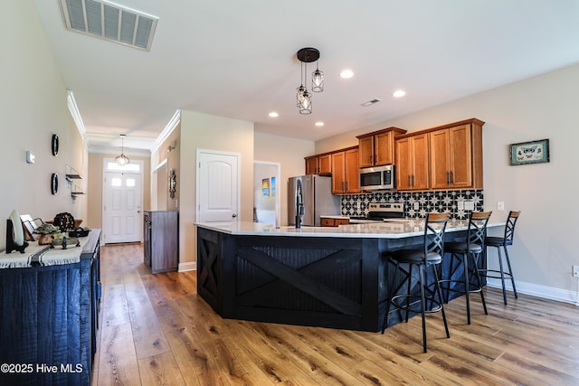 1187 S Brook Rd, Winnabow, NC 28479 - kitchen with stainless steel appliances, brown cabinets, light wood-style floors, a peninsula, and light countertops