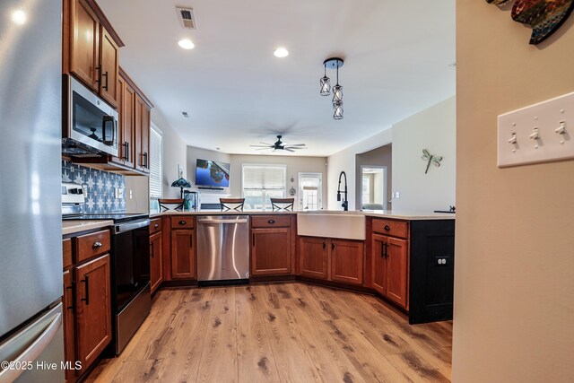 1187 S Brook Rd, Winnabow, NC 28479 - kitchen with stainless steel appliances, a ceiling fan, light wood-type flooring, a peninsula, and brown cabinets