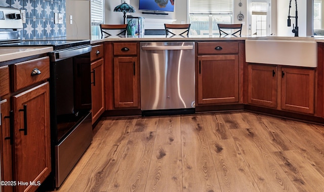 1187 S Brook Rd, Winnabow, NC 28479 - kitchen featuring appliances with stainless steel finishes, decorative backsplash, light wood finished floors, and brown cabinets