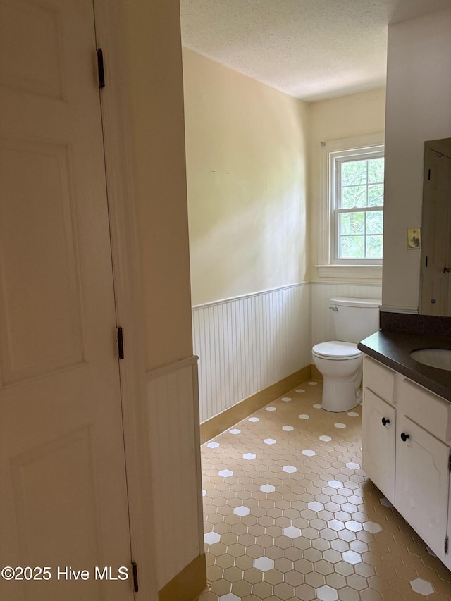 1102 Raleigh Road Parkway W, Wilson, NC 27896 - bathroom featuring wainscoting, vanity, toilet, a textured ceiling, and a closet