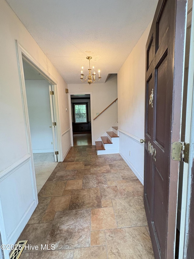 1102 Raleigh Road Parkway W, Wilson, NC 27896 - entryway with a chandelier, baseboards, stairs, a textured ceiling, and stone finish floors