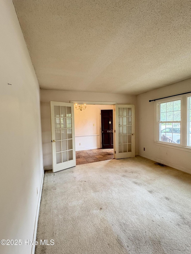 1102 Raleigh Road Parkway W, Wilson, NC 27896 - carpeted spare room with french doors, a chandelier, a textured ceiling, and baseboards