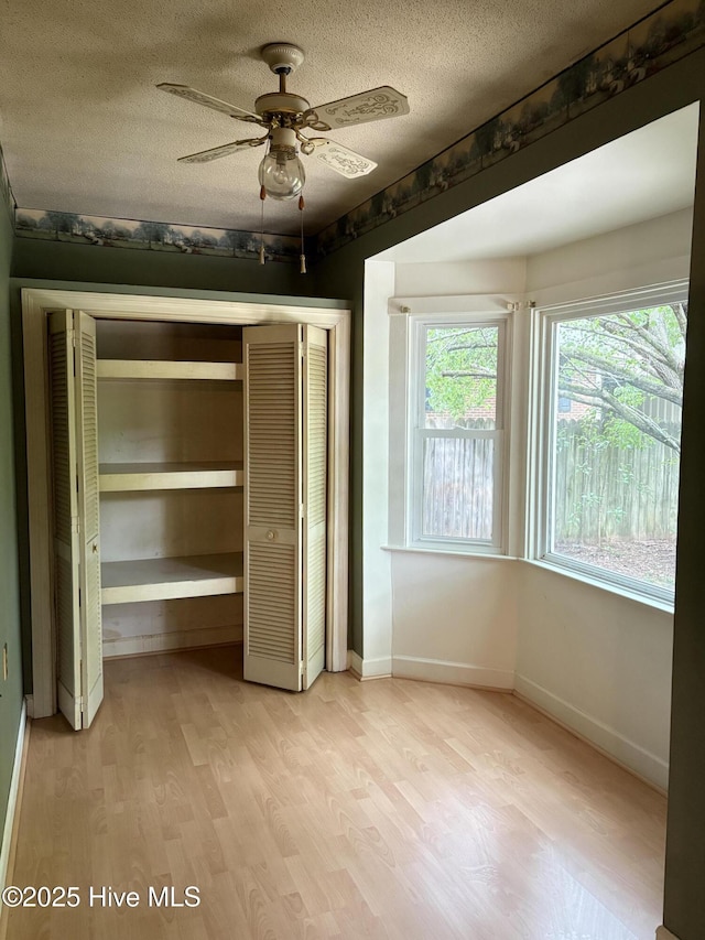 1102 Raleigh Road Parkway W, Wilson, NC 27896 - unfurnished bedroom featuring light wood-type flooring, a closet, a textured ceiling, baseboards, and a ceiling fan
