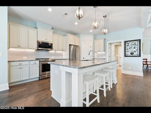 2385 Red Birch Trl NE, Leland, NC 28451 - kitchen with appliances with stainless steel finishes, a sink, decorative backsplash, dark wood-style flooring, and a center island with sink