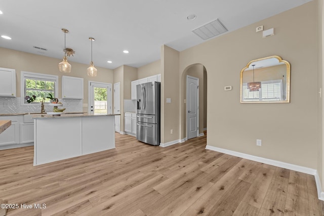 433 Shepherd Trl, Aberdeen, NC 28315 - kitchen with stainless steel fridge with ice dispenser, decorative backsplash, white cabinets, light wood-type flooring, and arched walkways